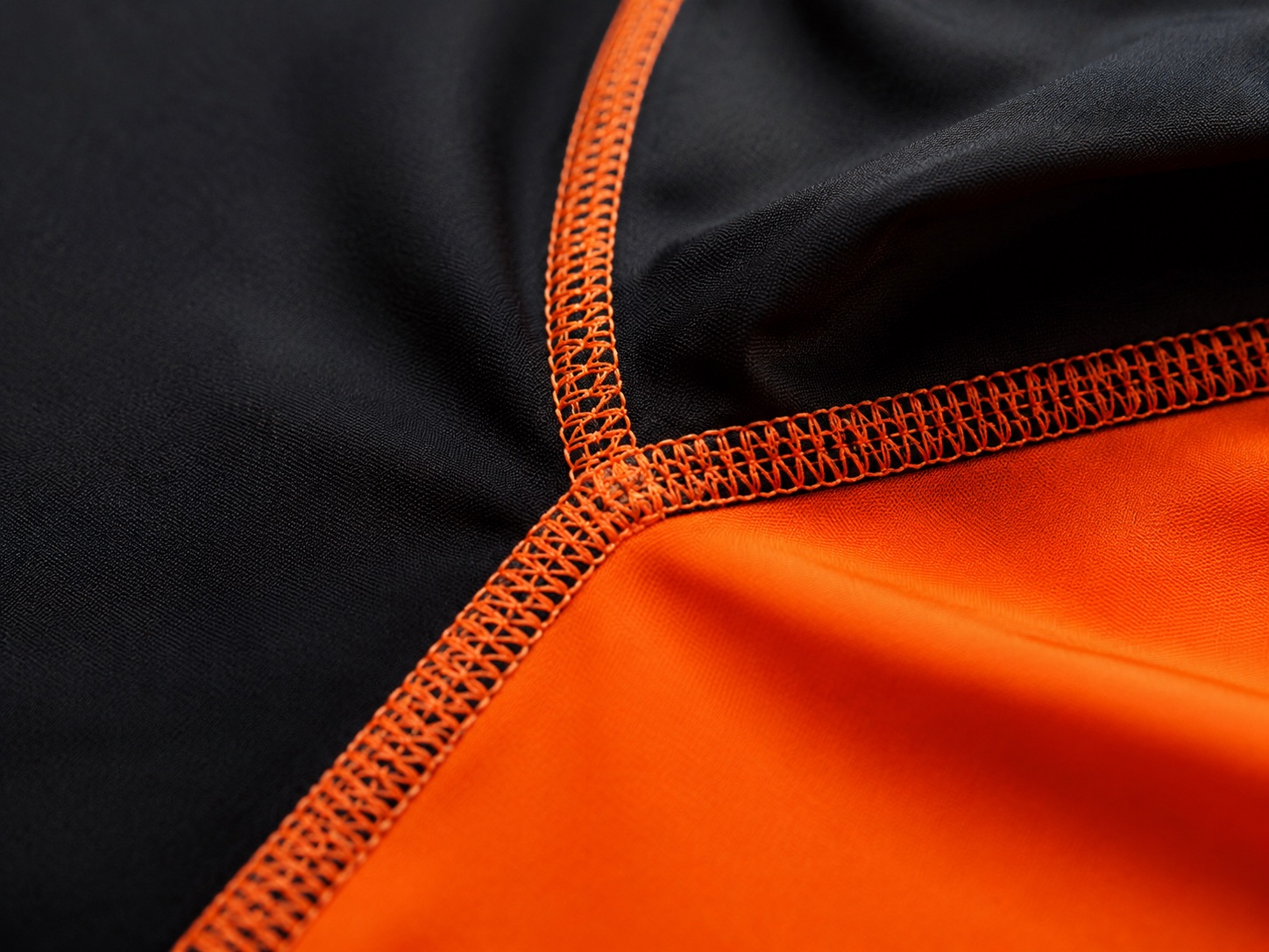 Macro close-up of a flatlock coverstitch seam in orange thread