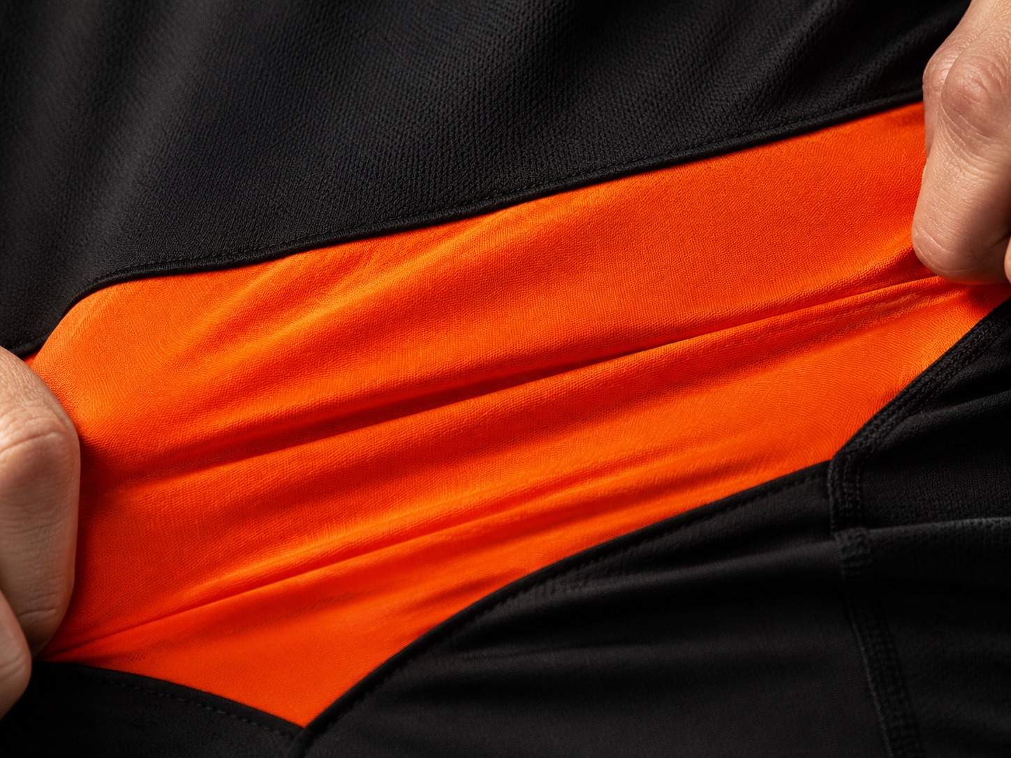 Macro close-up of an orange stretch panel set into black fabric