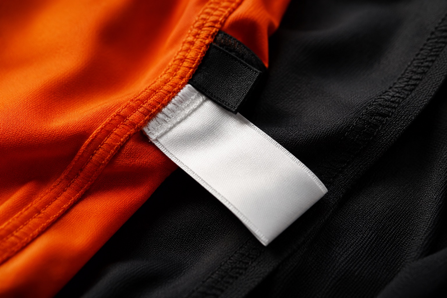 Close detail of a woven size tab and care label at a garment side seam