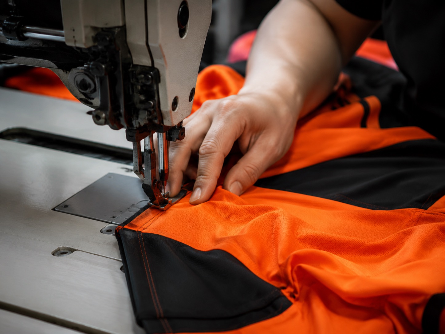 Operator adding a bar tack reinforcement to a finished sportswear garment