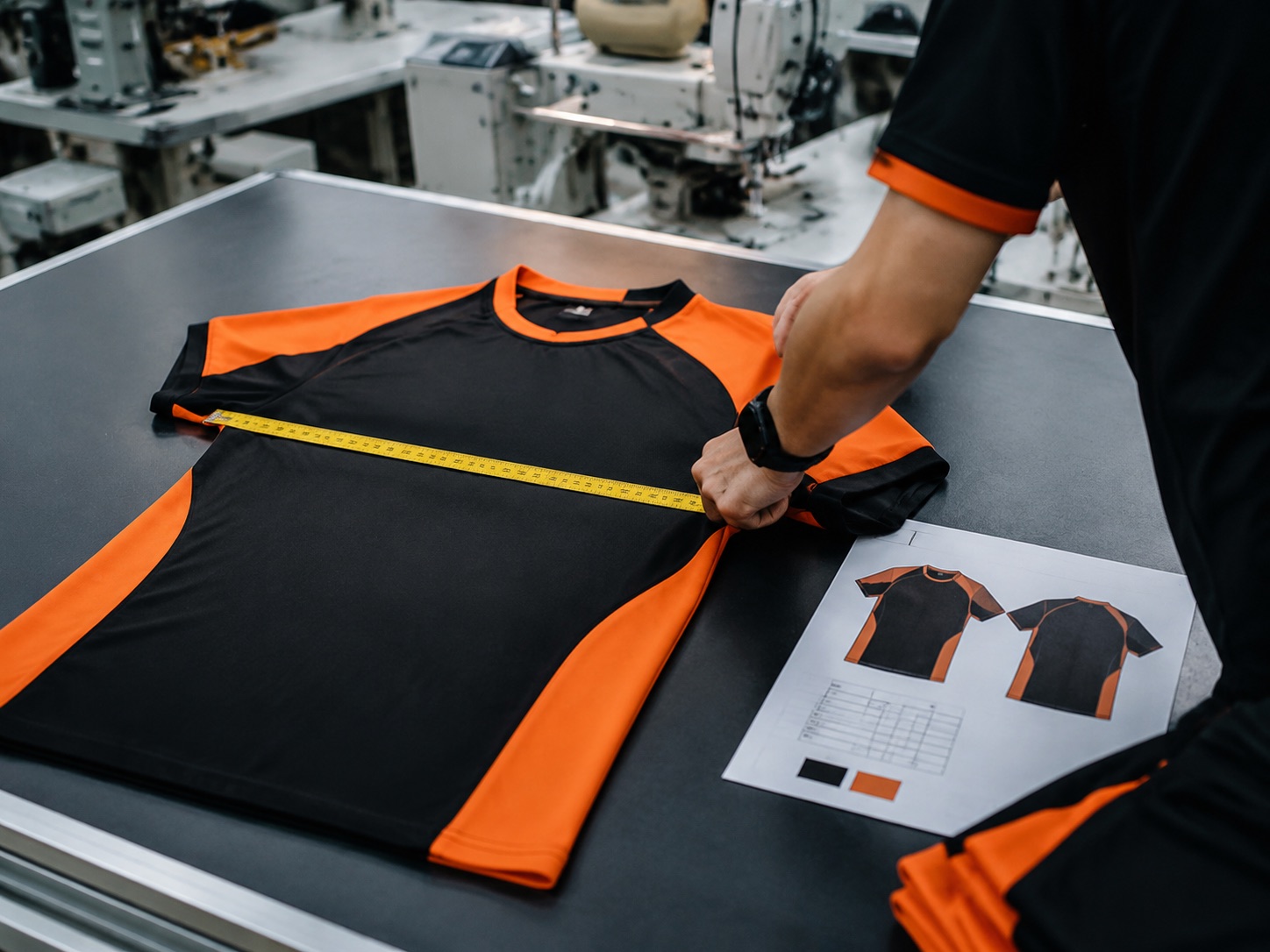 Sample garment being measured against a specification sheet with a tape measure