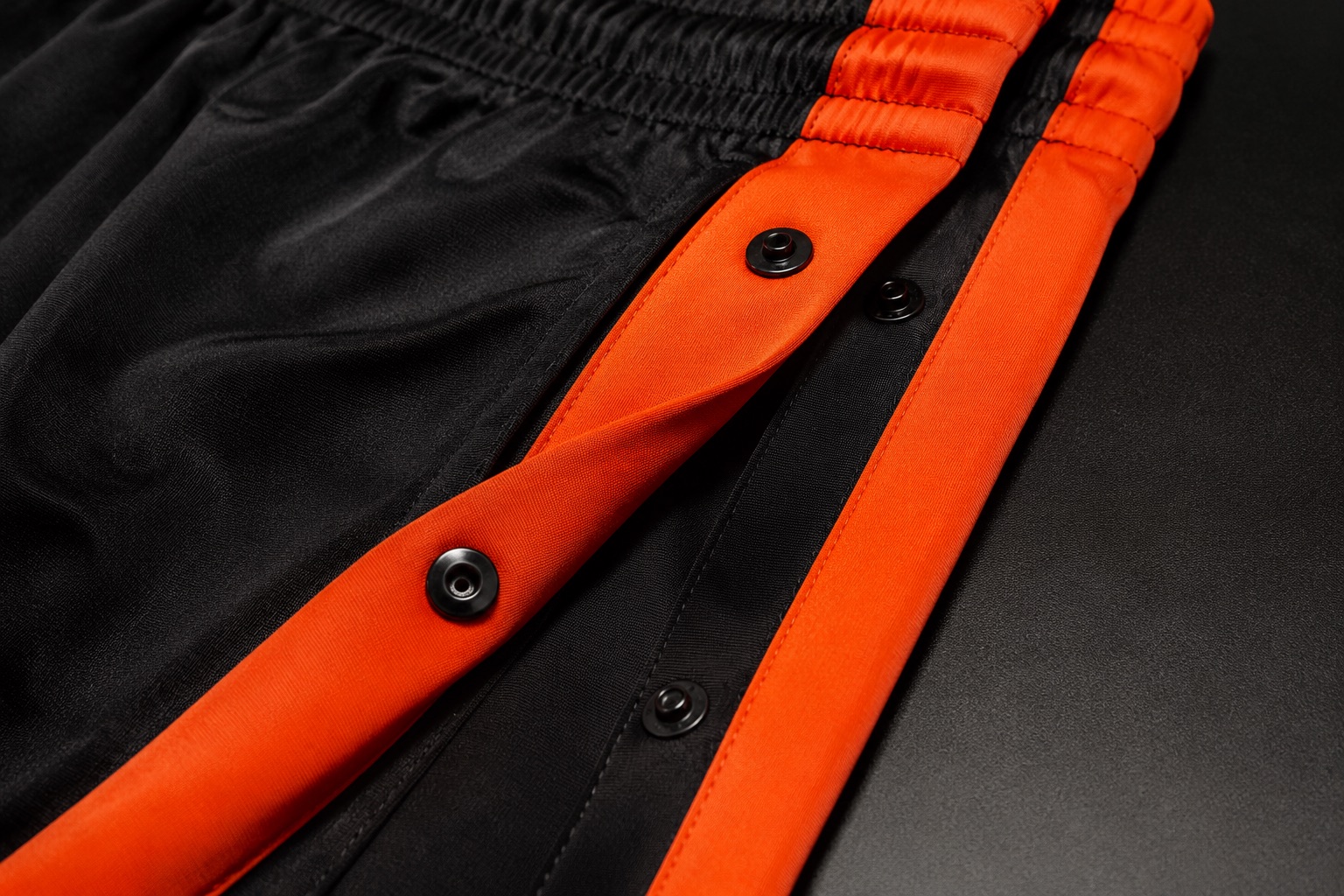 Close detail of the popper fastening on a pair of tear-away basketball warm-up pants