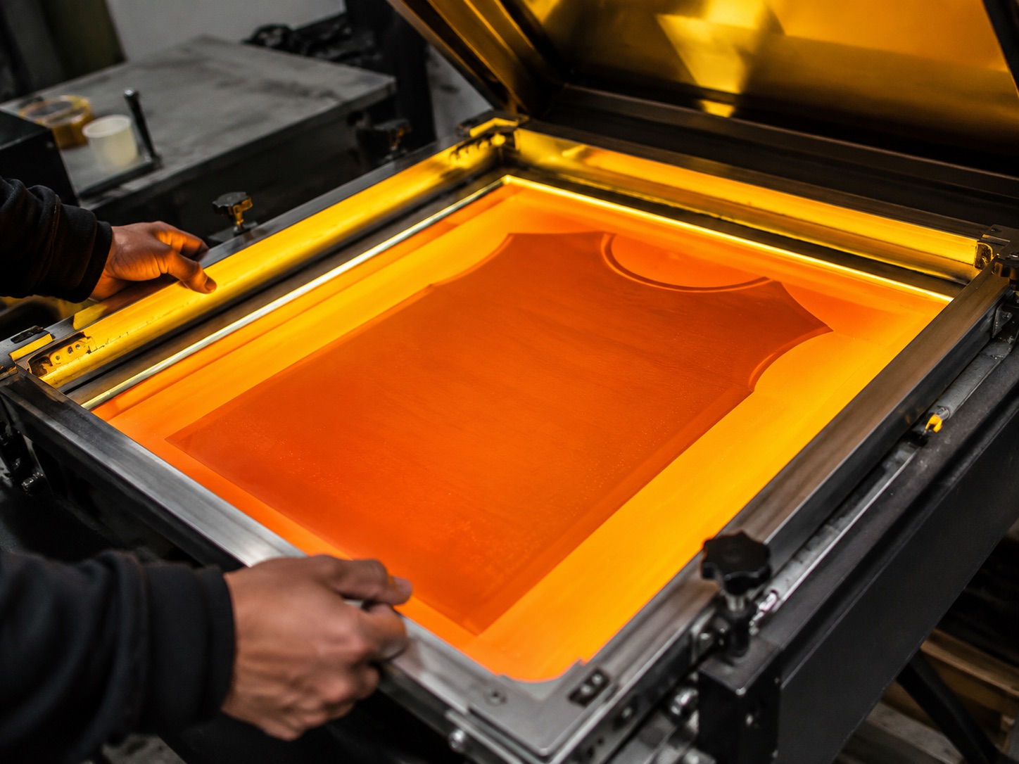 Emulsion-coated screen being exposed to create a printing stencil