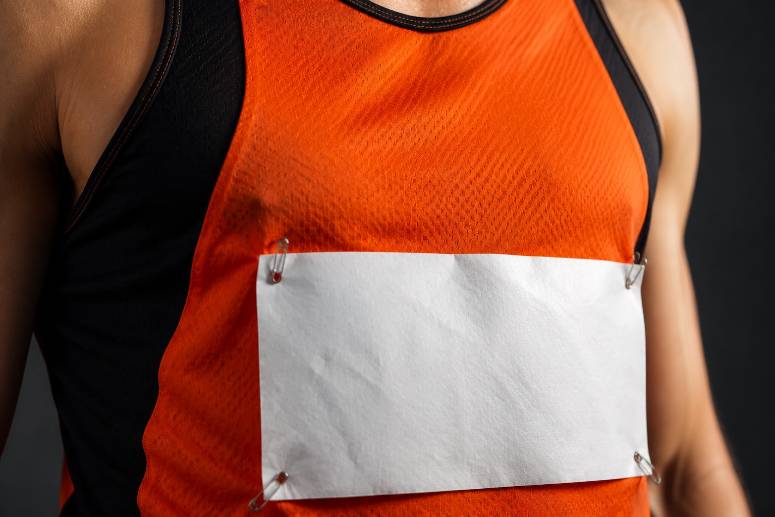 Close detail of a race bib pinned to the front of an athletics vest