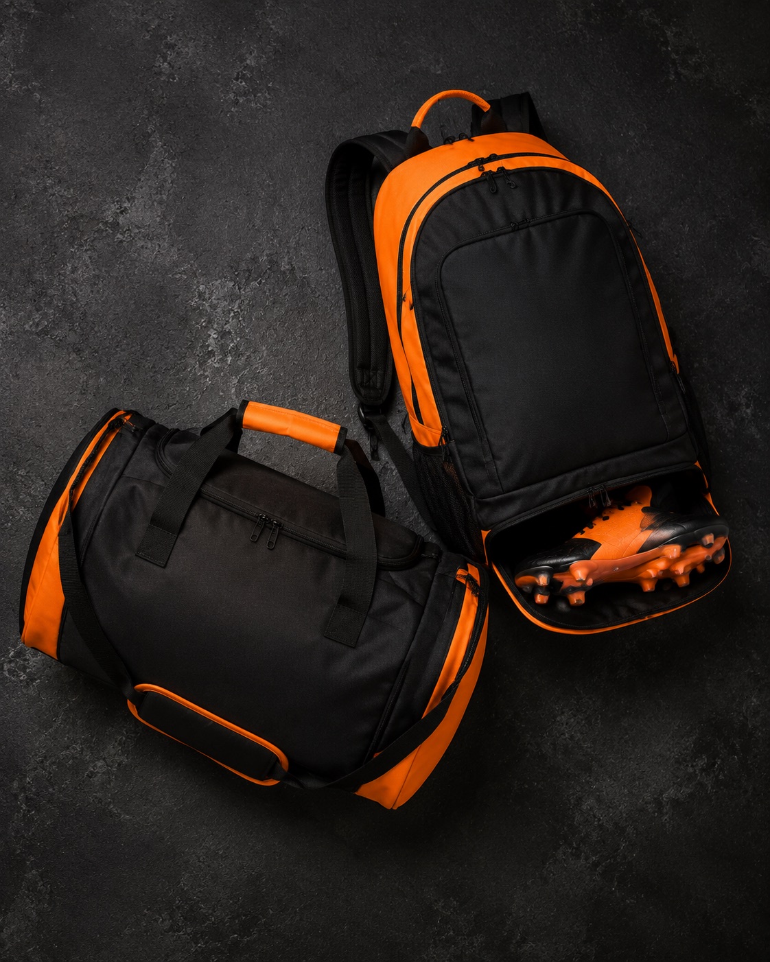 Black and orange football kit backpack with boot compartment beside a holdall