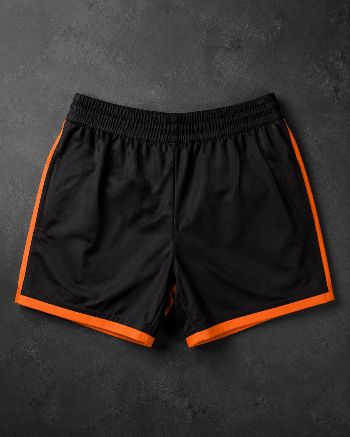 Heavy woven rugby match shorts with contrast trim, flat lay on dark charcoal