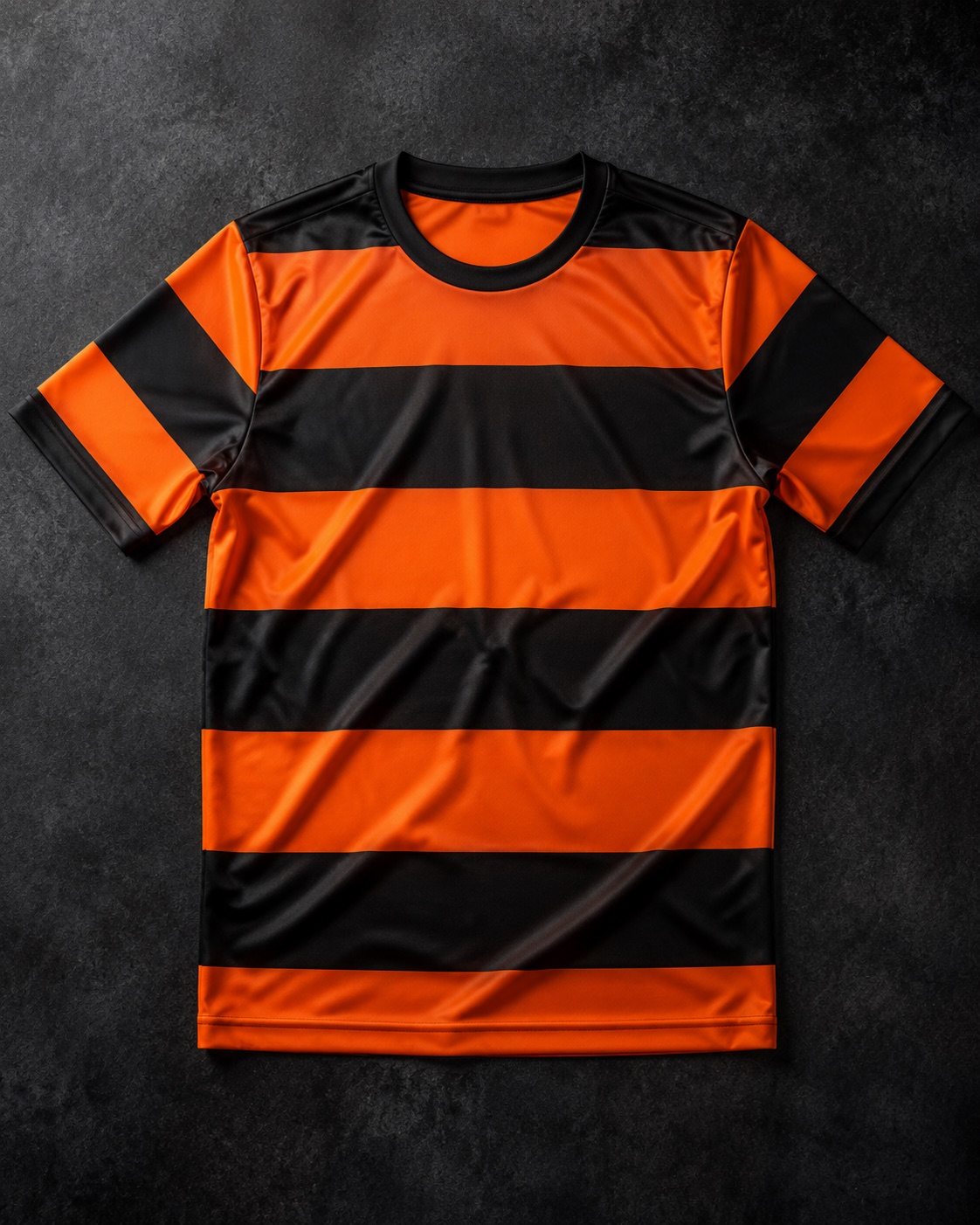 Custom orange and black hooped football match jersey, flat lay on dark charcoal