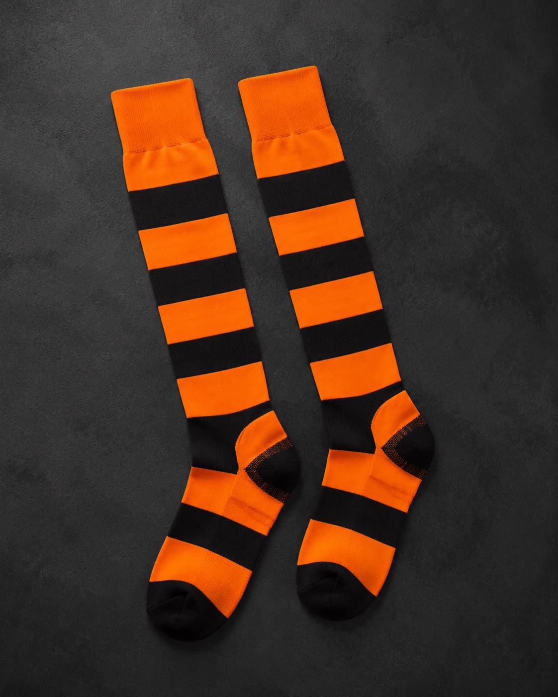 Tall hooped rugby socks, flat lay on dark charcoal