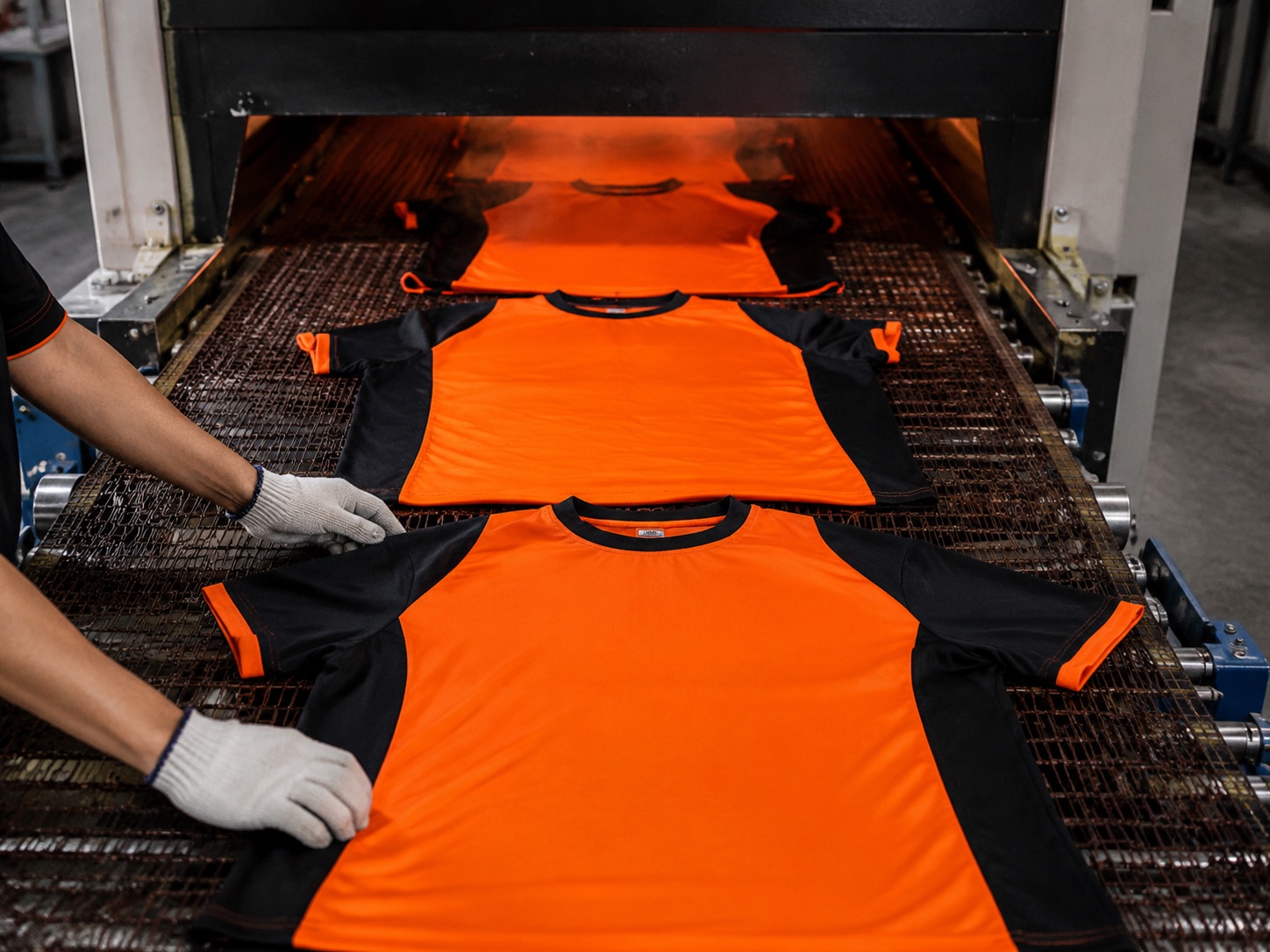 Printed garments passing through a curing dryer on a conveyor